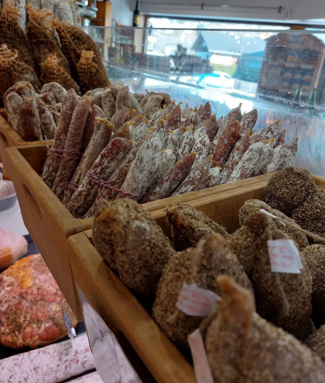 Saucissons secs maison rangés dans des cagettes en bois sur l'étal